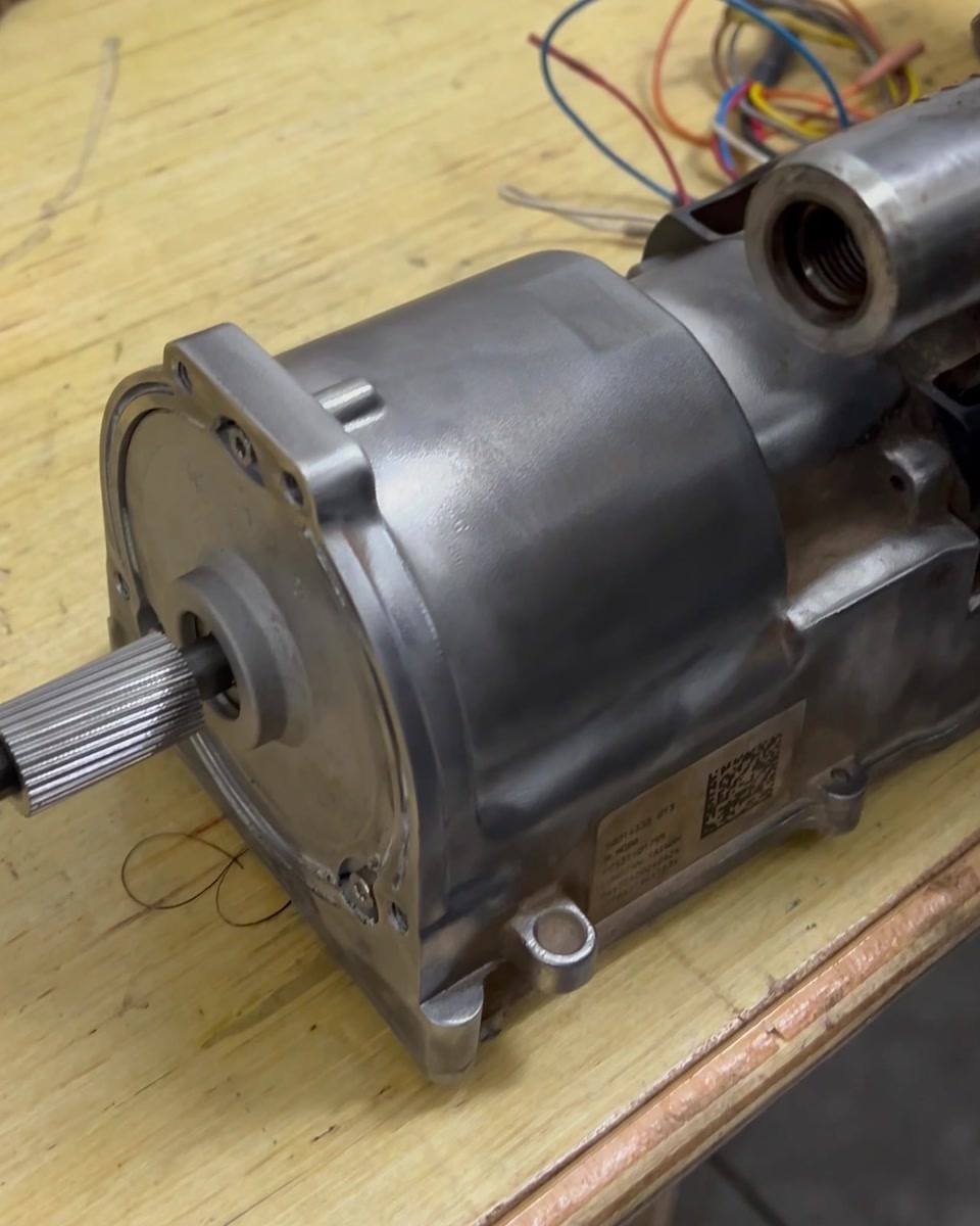 Electric power steering rack with its assist motor and splined shaft exposed on a workbench during electric steering rack repair in Pretoria