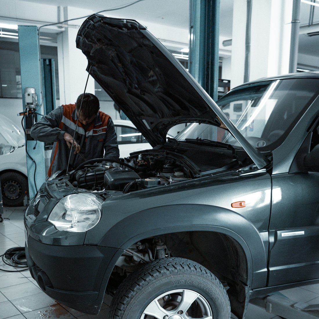 A CV Master technician working under the bonnet of a vehicle on the workshop floor